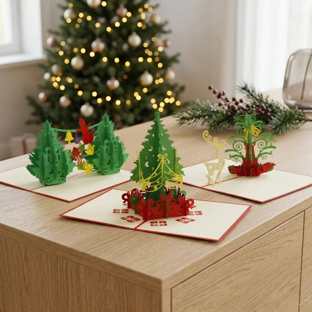 Drei geöffnete Pop-Up-Karten aus dem Set Tannenbaumfreude auf einem Sideboard vor warmen Weihnachtslichtern.