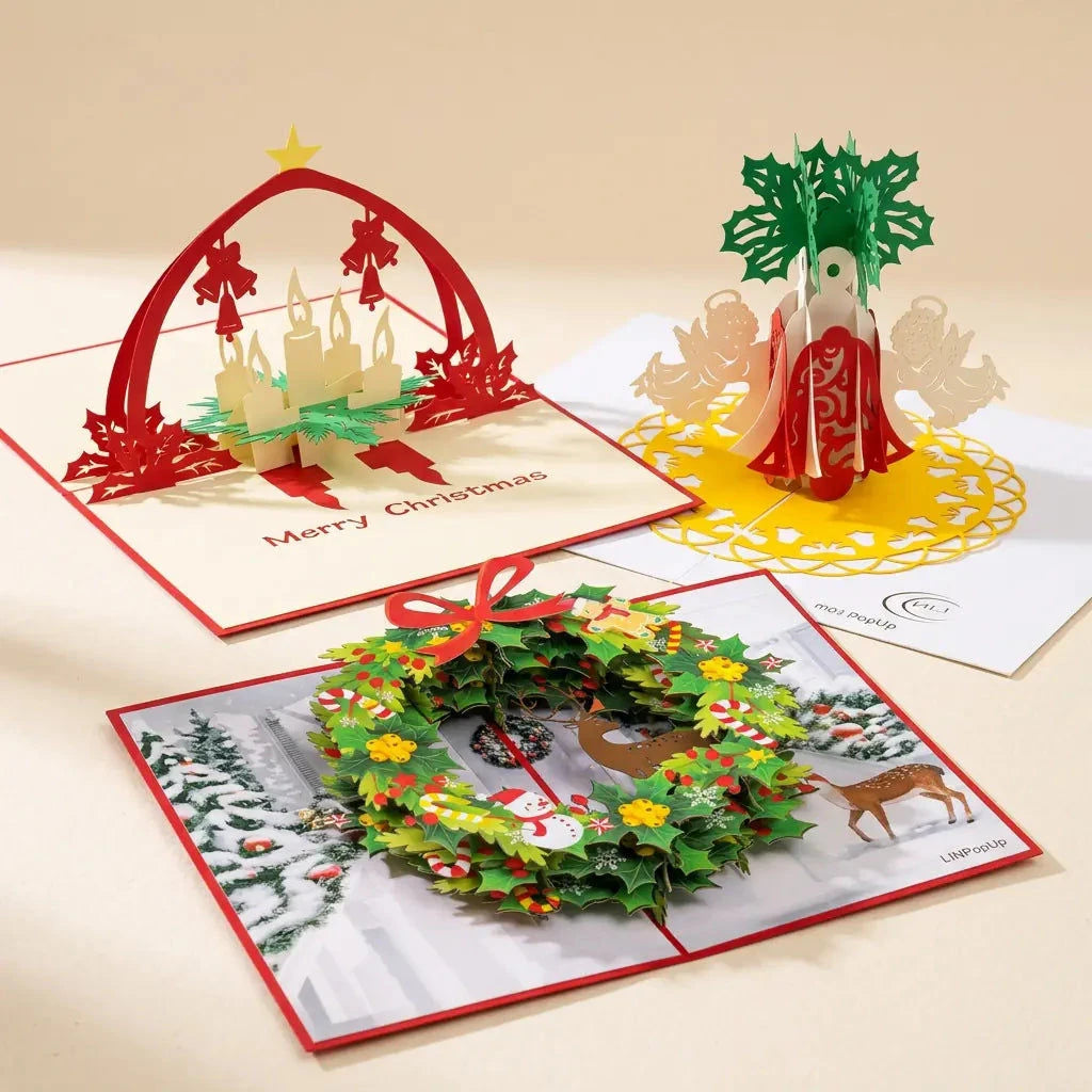 Drei geöffnete LINPopUp Pop-Up-Weihnachtskarten im Set Adventsfreude: Adventskranz mit Kerzen und rotem Bogen, bunter Weihnachtskranz sowie rot-cremefarbene Weihnachtsglocken mit Engeln