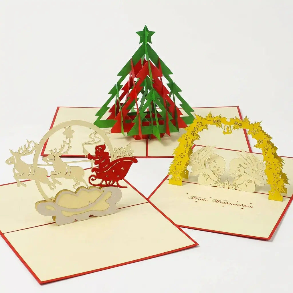 Drei geöffnete LINPopUp Pop-Up-Weihnachtskarten mit rot-grünem Tannenbaum, Weihnachtsmann im Rentierschlitten und zwei Engeln unter einem Mistelbogen
