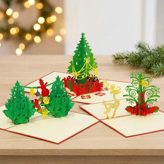 Drei geöffnete Pop-Up-Weihnachtskarten des Sets Tannenbaumfreude mit geschmückten Bäumen, Geschenken und gelbem Rentier auf einem Holztisch vor Weihnachtslichtern