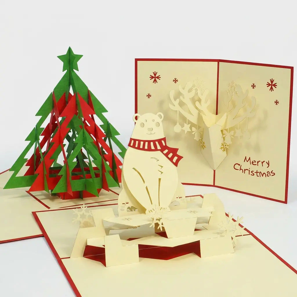 Drei geöffnete LINPopUp Pop-Up-Weihnachtskarten: rot-grüner Tannenbaum, Eisbär mit rotem Schal im Schnee und Rentierkopf mit geschmücktem Geweih