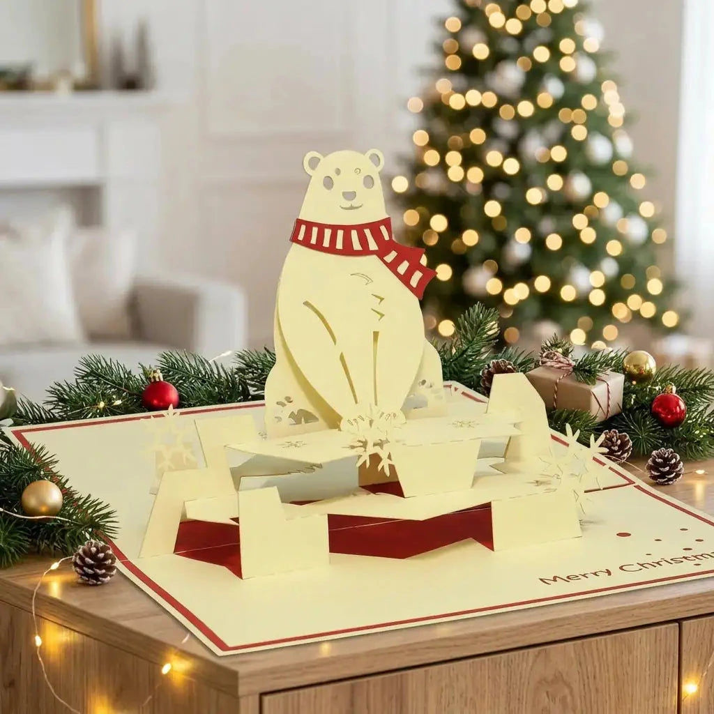 Offene Eisbär-Pop-Up-Weihnachtskarte auf einem Sideboard mit Tannengrün, Weihnachtskugeln und warmen Lichtern