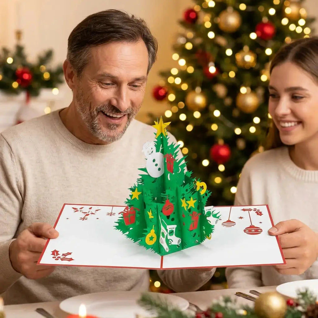 Ein Vater betrachtet freudig die kleine Weihnachtsbaum-Pop-Up-Karte in seinen Händen, während seine Tochter neben ihm lächelt