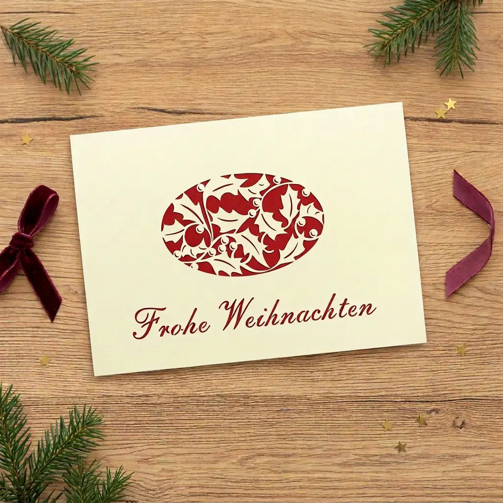 Sehr hell zitronengelbe Weihnachtskarte mit eckigen Ecken, rotem Blattornament und „Frohe Weihnachten“ auf einem Eichentisch.