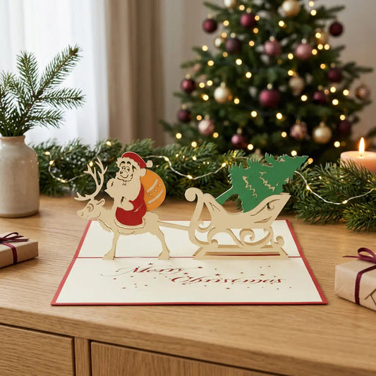 Geöffnete Pop-Up-Karte mit Weihnachtsmann auf einem Rentier und Schlitten mit grünem Tannenbaum auf einem Eichensideboard, umgeben von Tannengrün, Lichtern und Weihnachtsgeschenken.